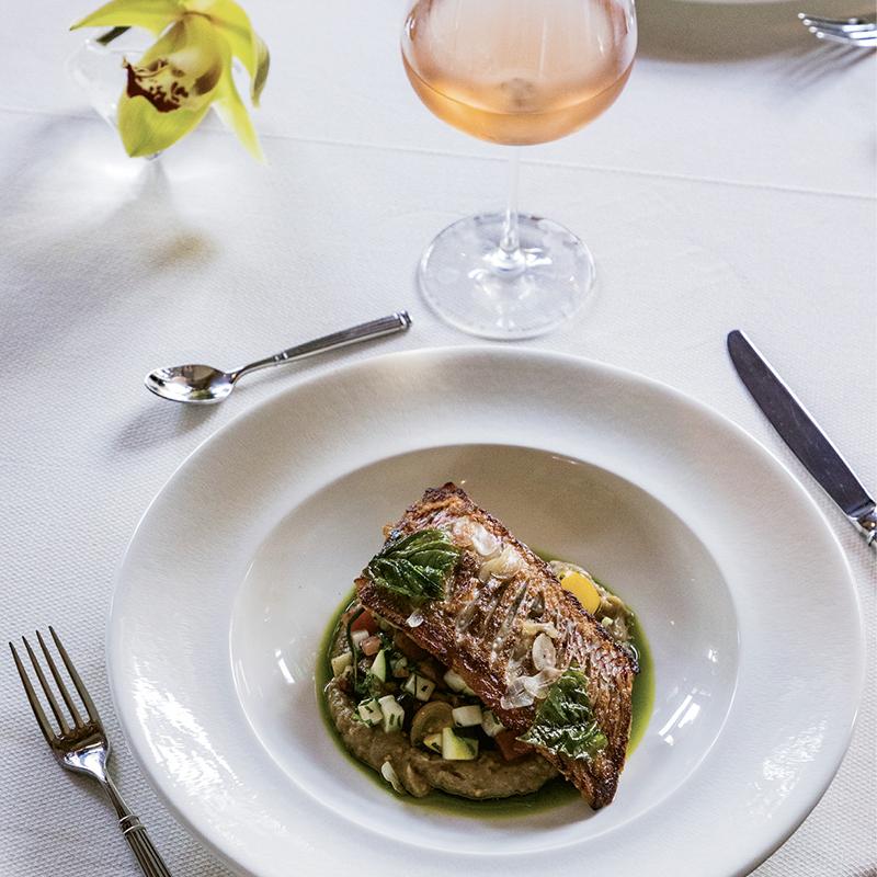 A filet of red snapper atop eggplant ratatouille