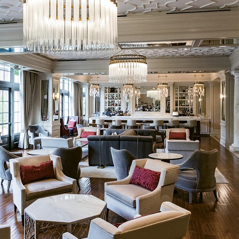 Guests gather at Gabrielle under custom chandeliers and coffered ceilings at the bar. 